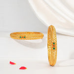Traditional gold-finish silver bangles with green and red gemstone accents on white background