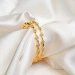 Gold-plated silver bangles with floral cubic zirconia set on white satin fabric