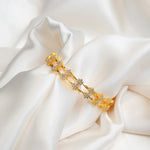 Gold-plated silver bracelet with floral cubic zirconia design on white silk fabric