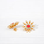 Gold stud earrings with red stone center, crystal accents, and pearl details on white background