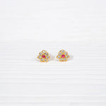 Gold-plated silver floral stud earrings with red and white stones on white background