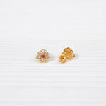 Gold-plated floral stud earrings with clear and red stones on a white background