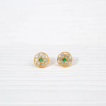 Round gold stud earrings with clear and green stones on white background