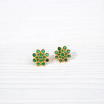 Gold plated floral stud earrings with green stones on white background, silver jewelry