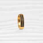 Gold-tone handcrafted ring with black accents and textured details on a white background