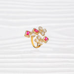 Gold-plated silver ring with pink square stones and white floral accents on a light background