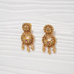 Antique gold-plated silver jhumka earrings with pearls and red gemstone accents on a white background.