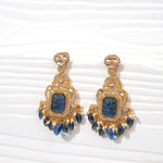 Gold-plated silver earrings with blue carved stone, pearl and crystal accents on white