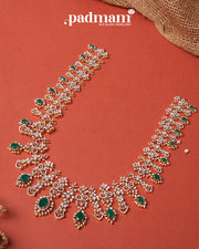 Intricate 92.5 silver necklace with green gemstones and white crystals on a terracotta background