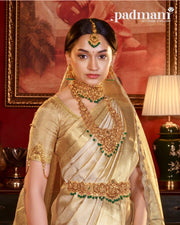 Woman in gold saree wearing ornate 92.5 silver jewelry set with green accents indoors