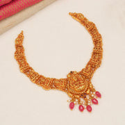 Gold-tone temple jewelry necklace with intricate deity motifs and pink stone danglers